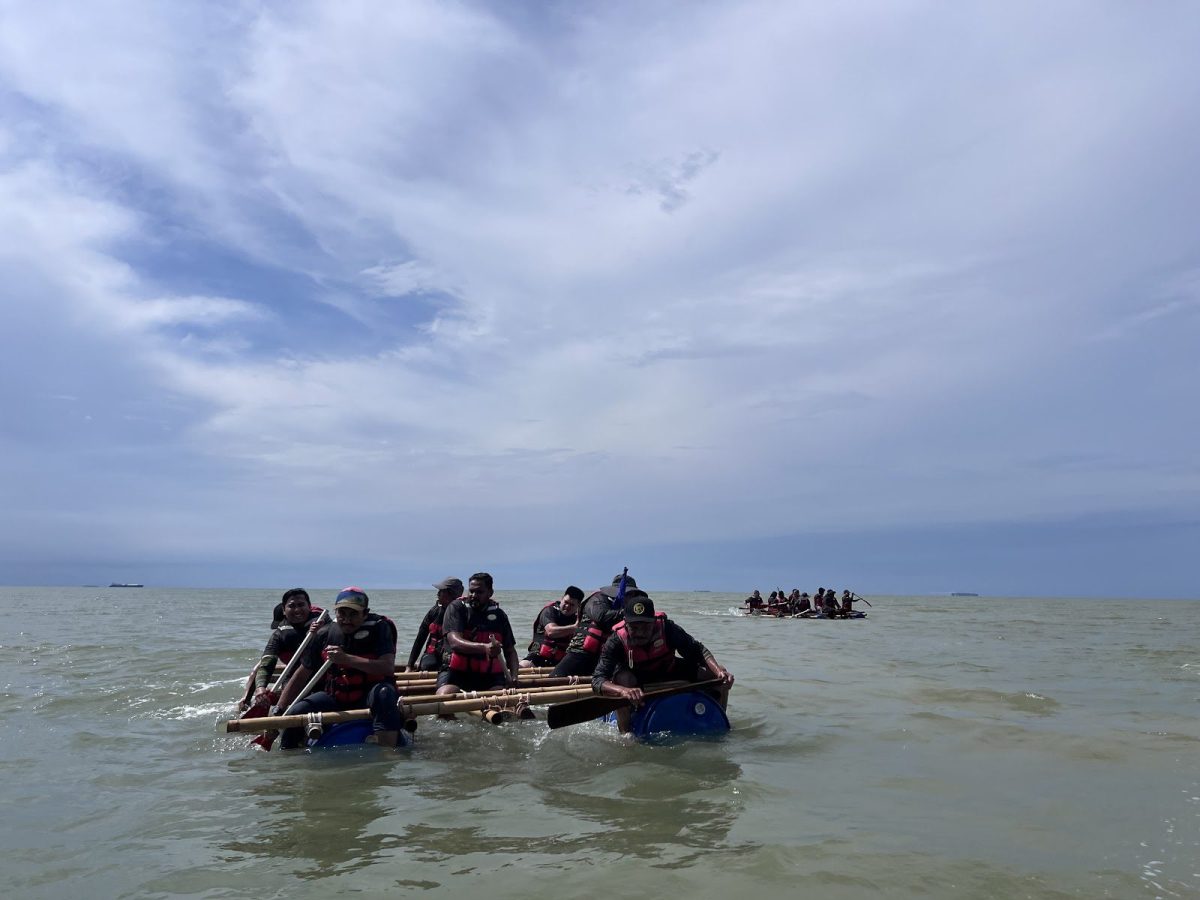 Team paddling a bamboo and drum raft at sea