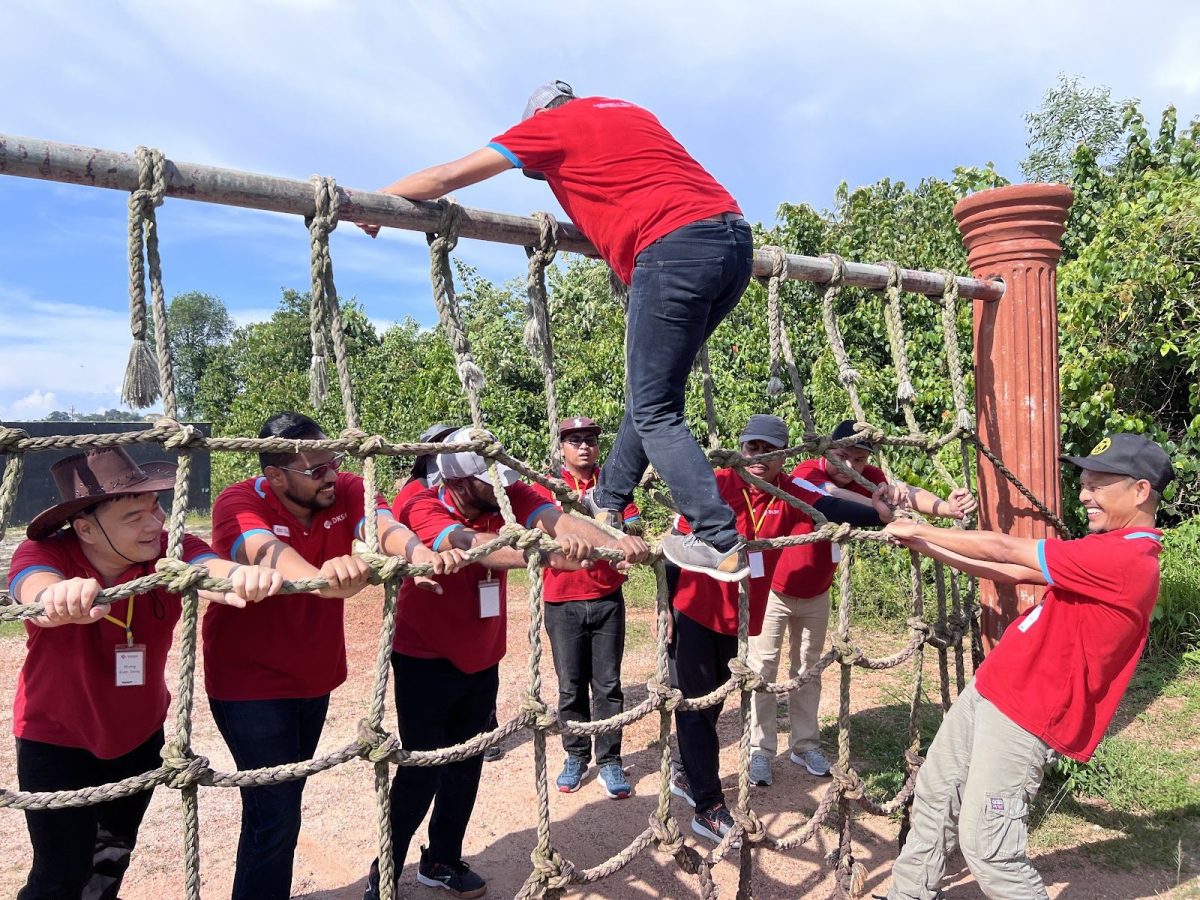 Team supporting a climber on a rope net obstacle